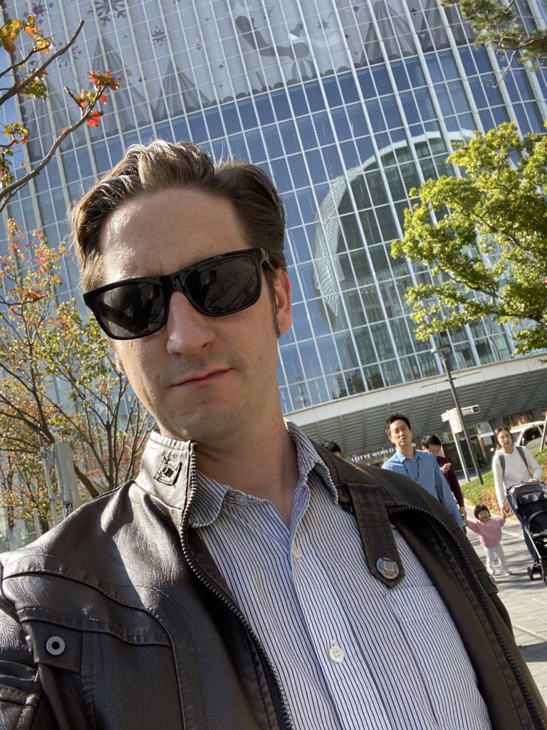 Me in front of a large building with a cute baby in the background.